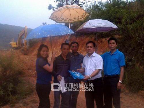 玉柴重工副总经理陈德坚(右二)在雨中为挖掘机用户送上服务月礼品