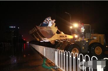  7月6日夜里，在武汉光谷大道金融港，现场积水最深处可达1米，来往居民通过需要靠铲车摆渡通行。