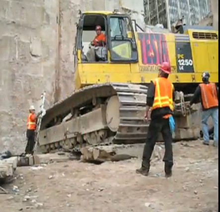 特斯塔公司吊机吊起小松pc1250-7挖掘机离开世贸中心